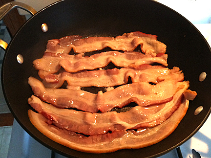 A serving of bacon cooking in my beloved Calphalon skillet.