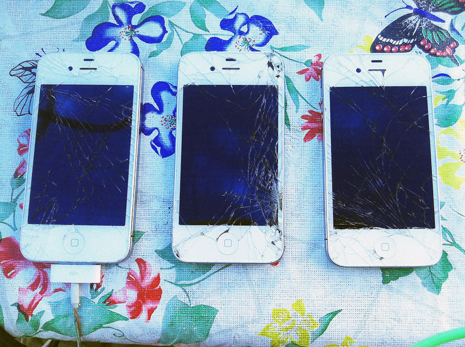 three white phones with badly cracked screens